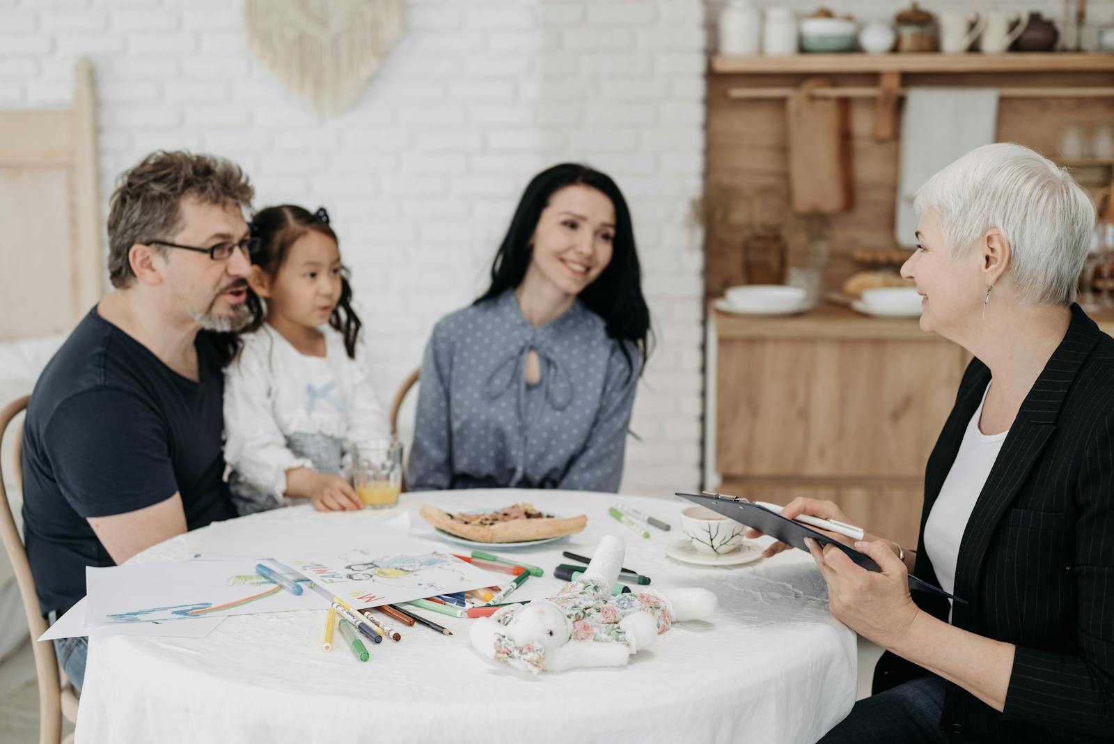 Parents meeting with a nanny candidate at a kitchen table during the nanny hiring process